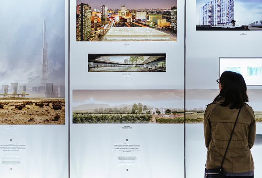Woman views architectural designs at Palau Robert exhibition, lit by ERCO spotlights.