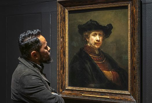 A man views a Rembrandt painting, showcasing how lighting affects visual perception in art.