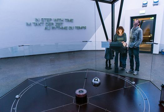 Family observes Foucaults pendulum demonstrating Earths rotation at Phänomenta, Lüdenscheid.
