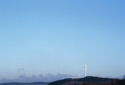 Wind turbine under a blue sky, symbolizing daylight and energy.