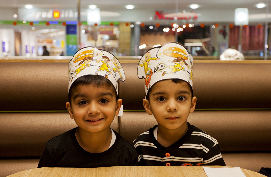 Two children wearing Pizza Hut paper crowns under ERCO LED lighting in a restaurant.