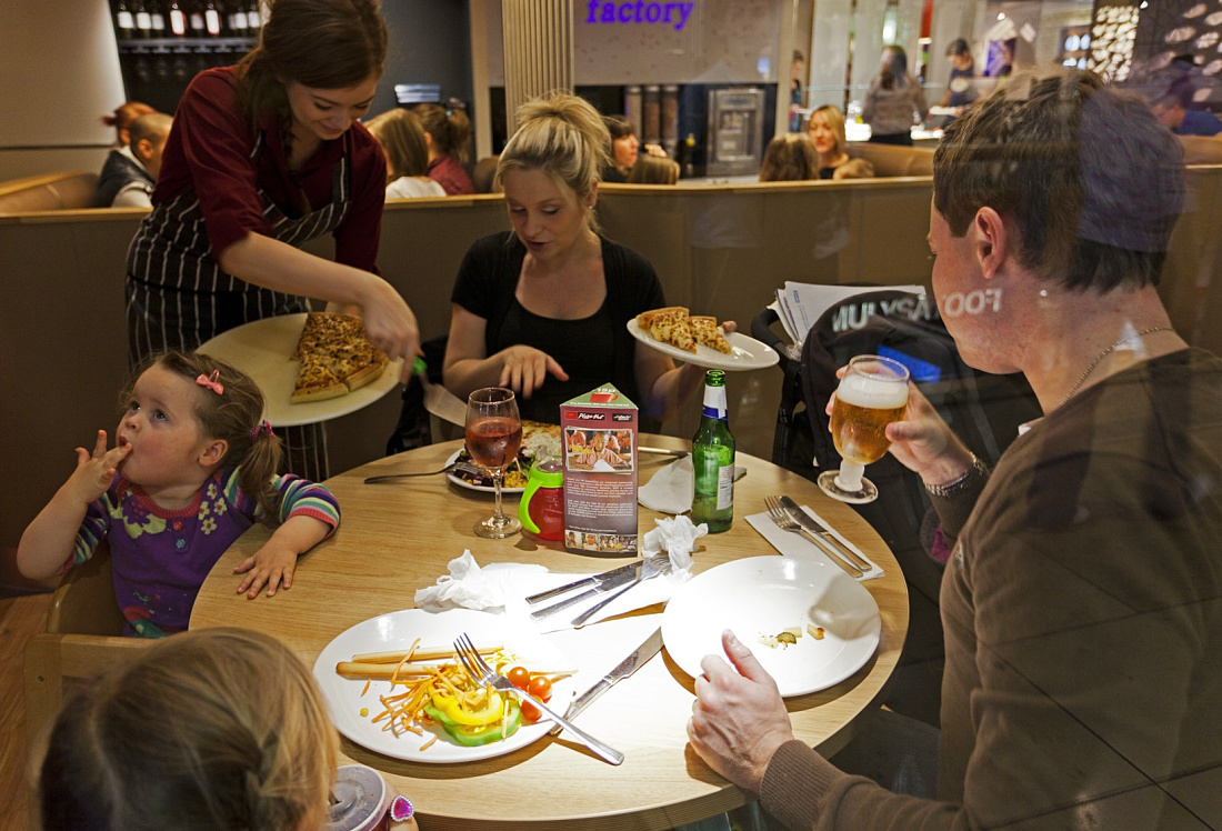 Pizza Hut restaurant: Family enjoying pizza under LED lighting.