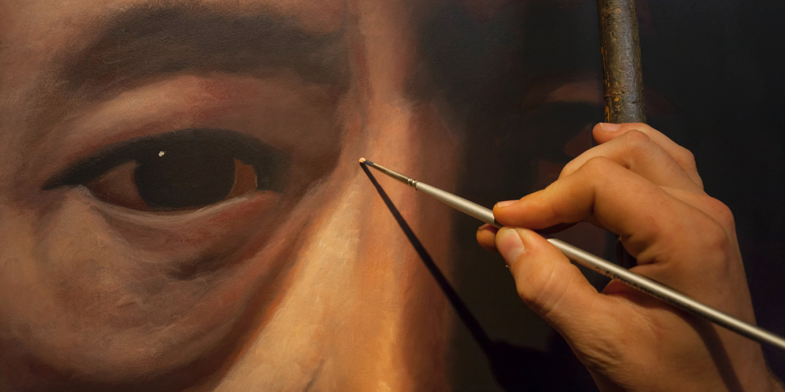 Close-up of a Matthew Penn portrait being painted, enhanced by ERCO lighting.