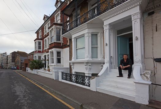 Matthew Penn sits on his studio steps in Margate, UK, using ERCO lighting to enhance his paintings.