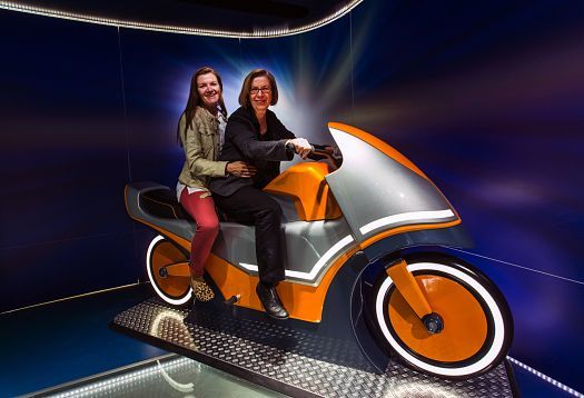 Visitors on a futuristic motorcycle exhibit at PS.Speicher Museum, illuminated by ERCO LED spotlights.
