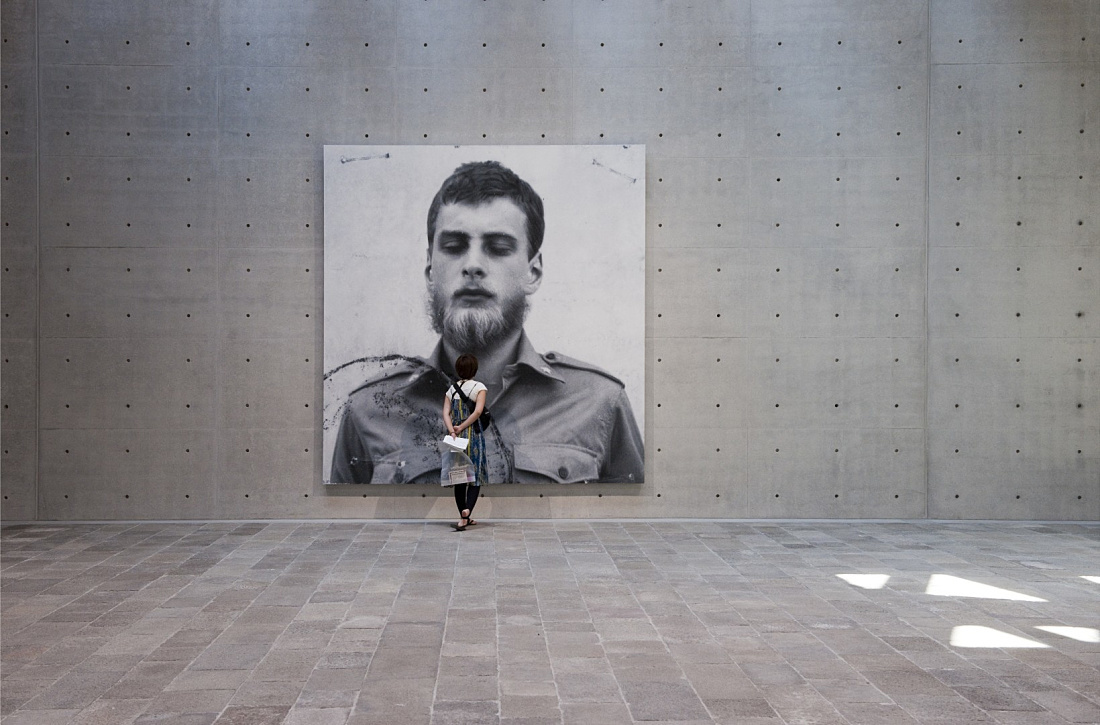 Visitor viewing a large portrait at Punta della Dogana, illuminated by ERCO lighting.