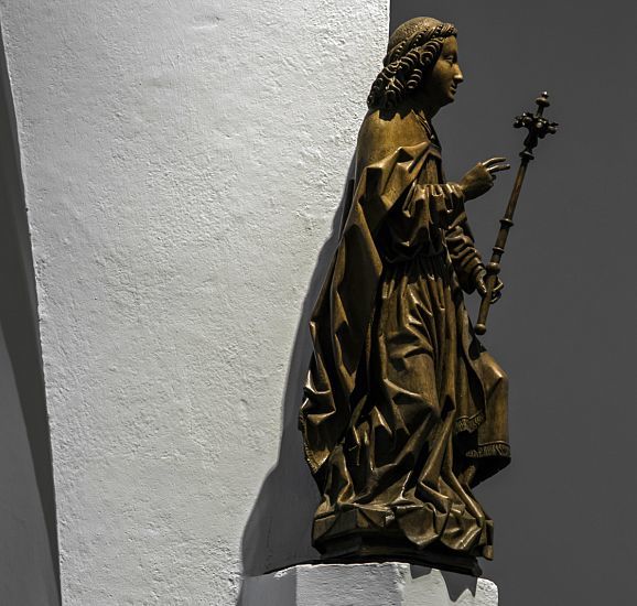 Wooden statue of a saint holding a cross in St. Mary's Birth Church, Grevenbroich.
