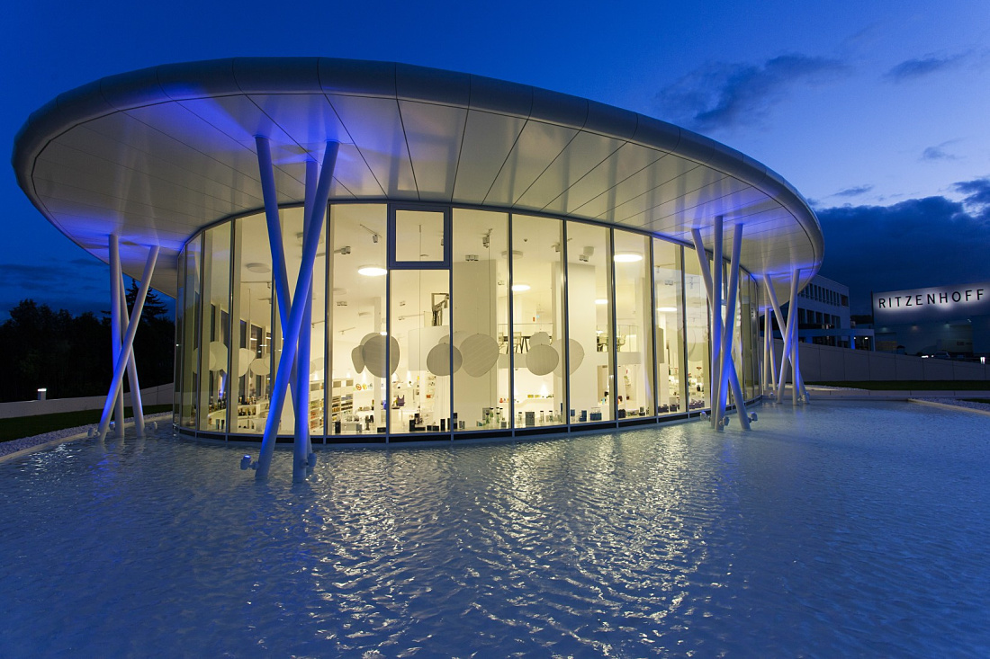 Ritzenhoff glass factory in Marsberg illuminated by ERCO lighting, showcasing modern architecture and glass products.