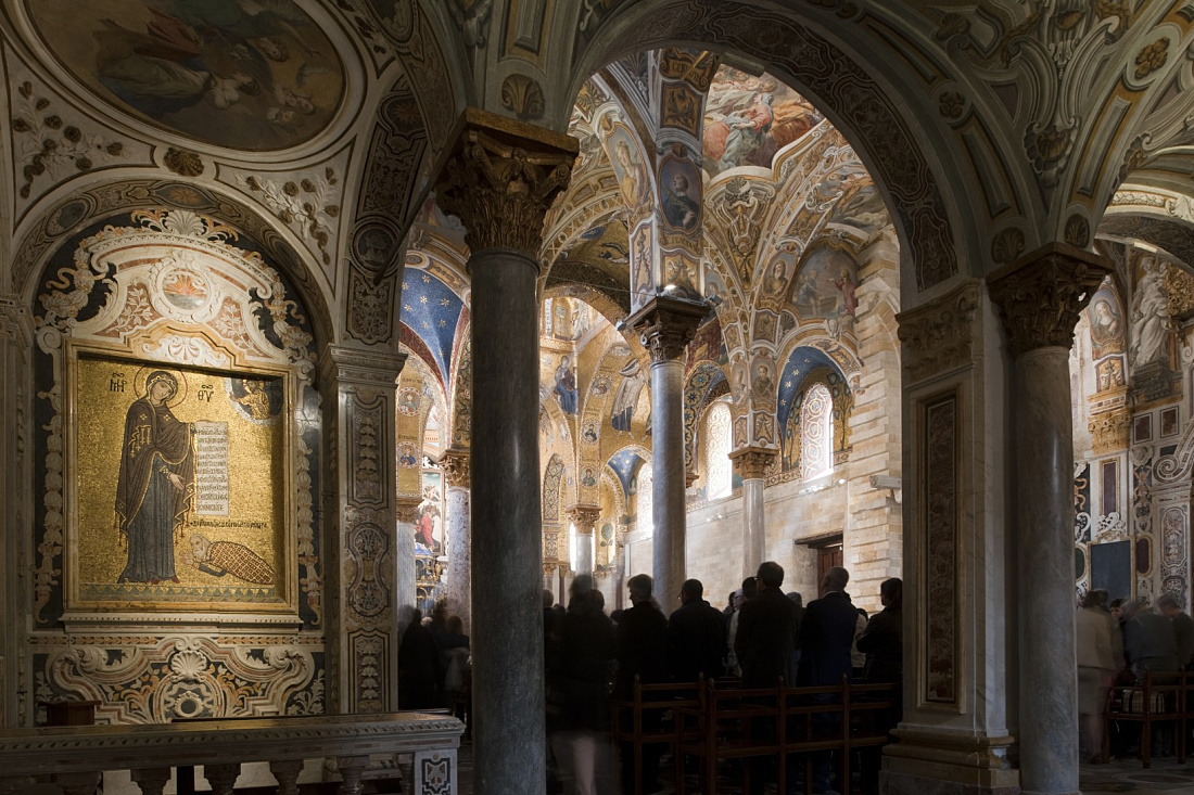 Interior of Santa Maria dell’Ammiraglio church, Palermo, featuring ornate ceilings and visitors.