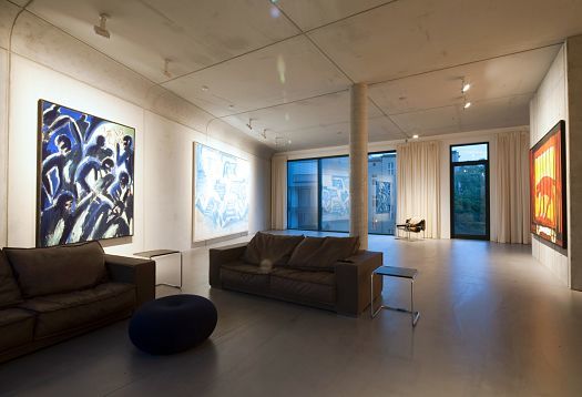 ERCO LED spotlights illuminate art in a Berlin living room with concrete walls and large paintings.