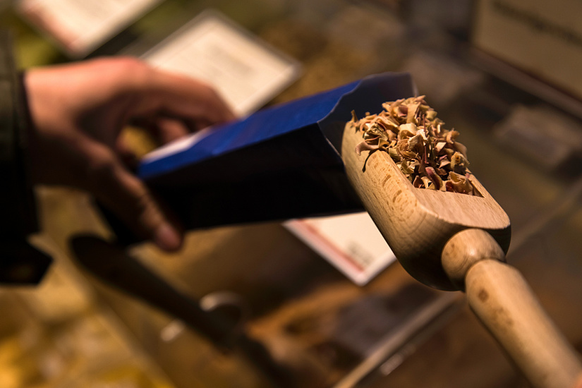 Schuhbeck's spices: Customer scoops spices with a wooden scoop, lit by ERCO LED lighting.