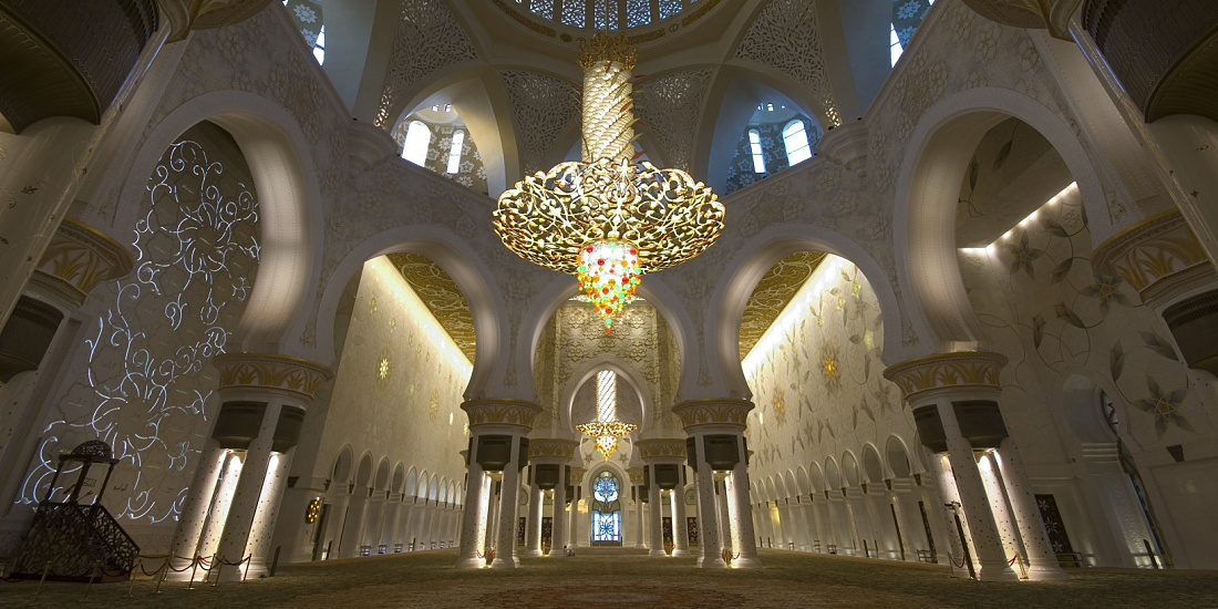 Interior of Sheikh Zayed Mosque featuring decorative lighting and ornate archways.
