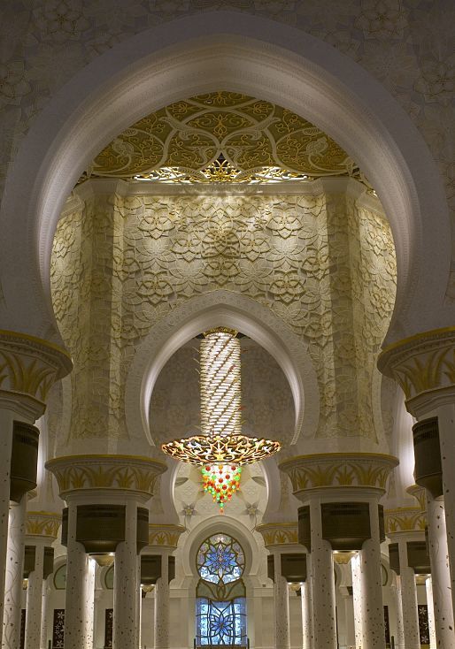 Interior of Sheikh Zayed Mosque featuring decorative lighting and ornate archways.