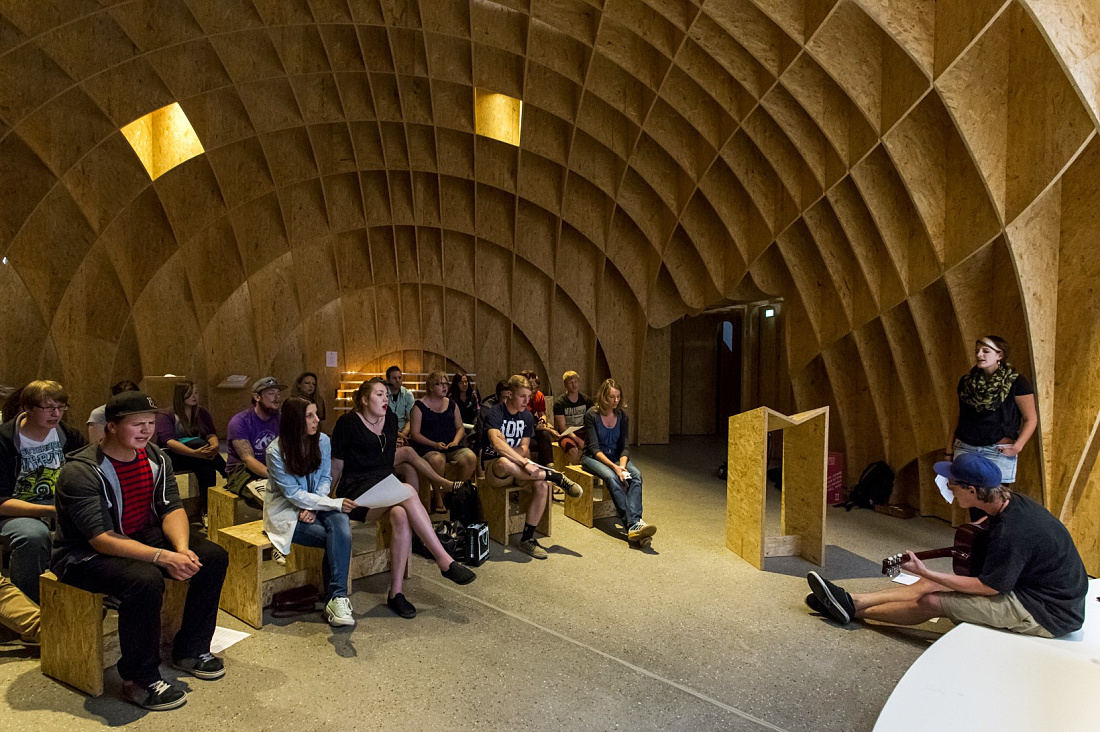 Interior of Siegerland Motorway Church featuring visitors and wooden structure for contemplation.