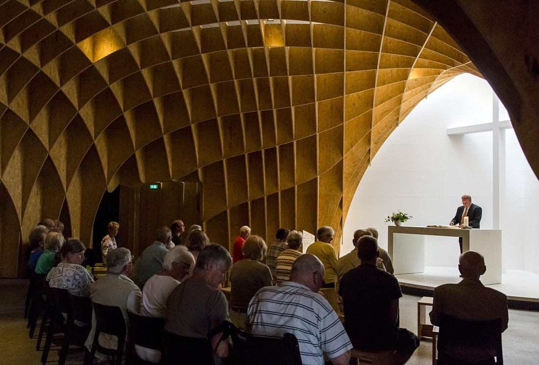 Interior of Siegerland Motorway Church featuring wooden structure and service attendees.
