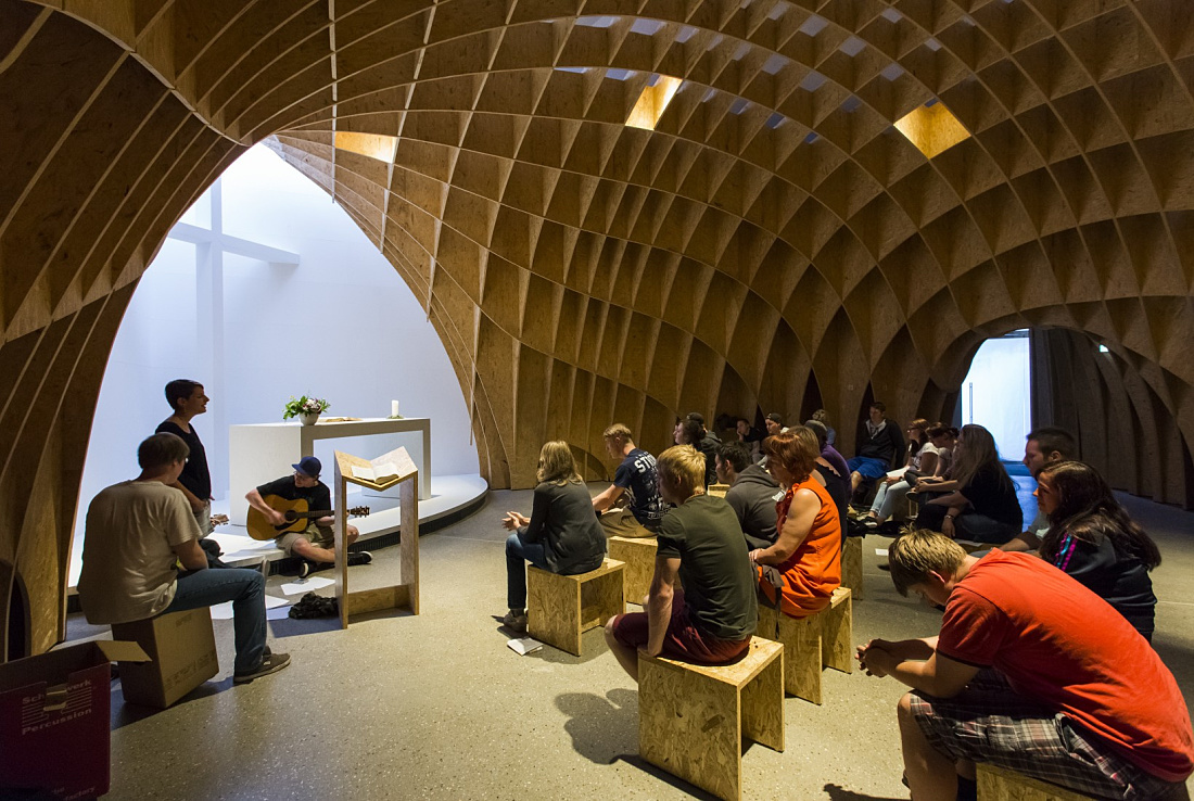 Interior of Siegerland Motorway Church featuring wooden structure and service attendees.
