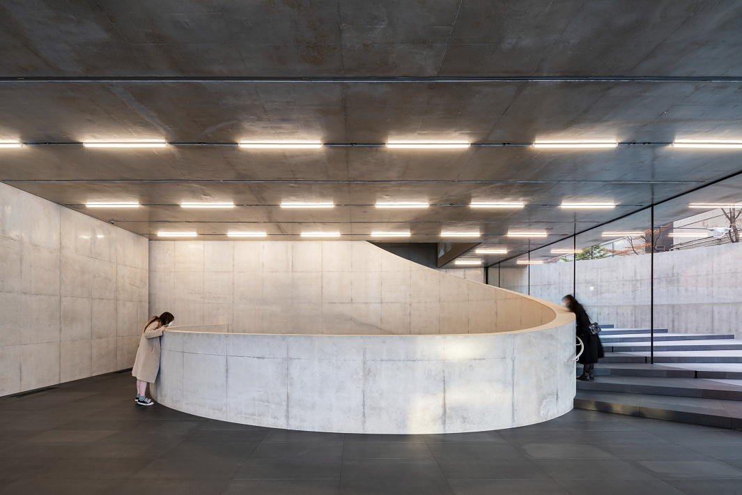 Interior of SongEun Art & Cultural Foundation featuring a concrete spiral staircase and ERCO lighting.