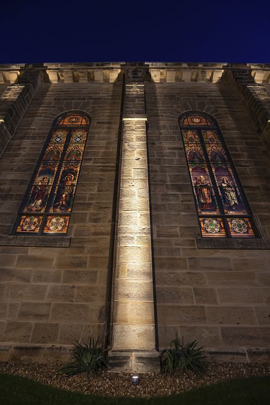 St. Joseph Church facade illuminated by ERCO Kona projectors, highlighting sandstone and stained glass.