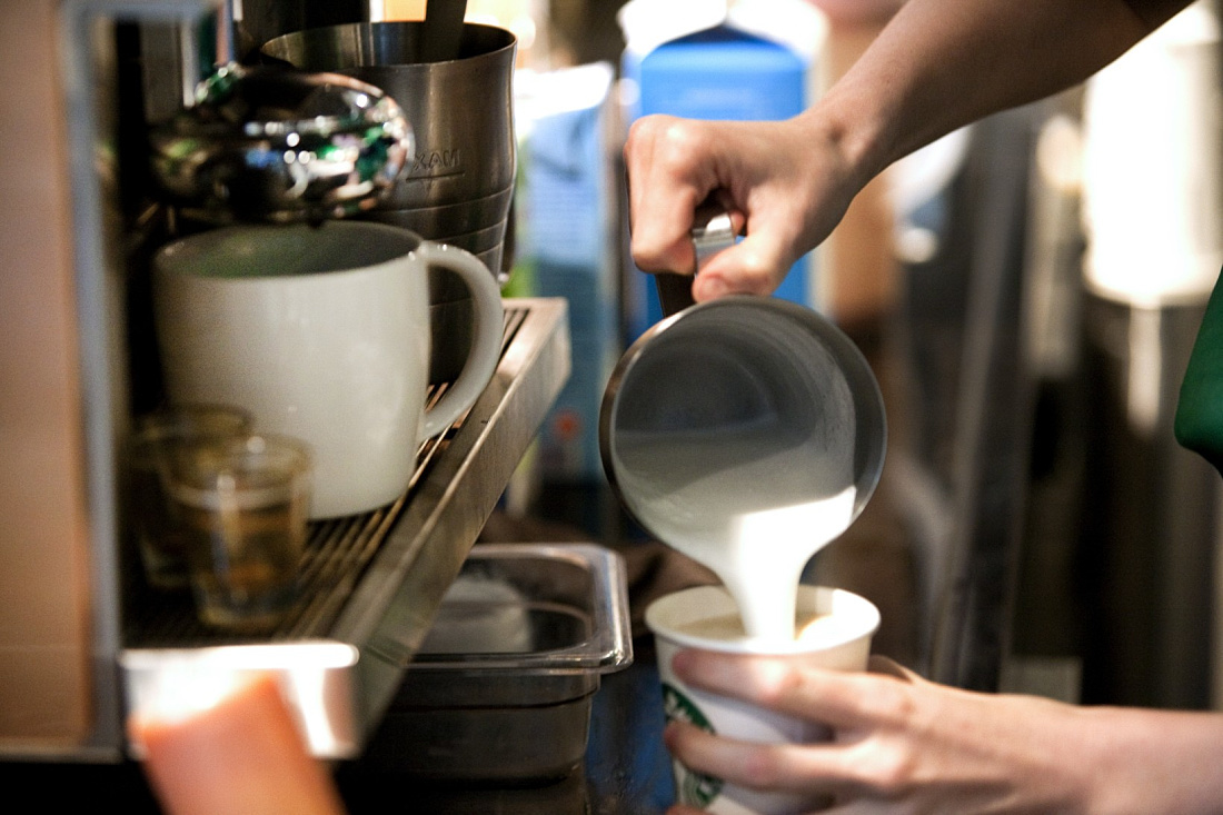 Pouring milk into a Starbucks coffee, part of the sophisticated lighting concept.