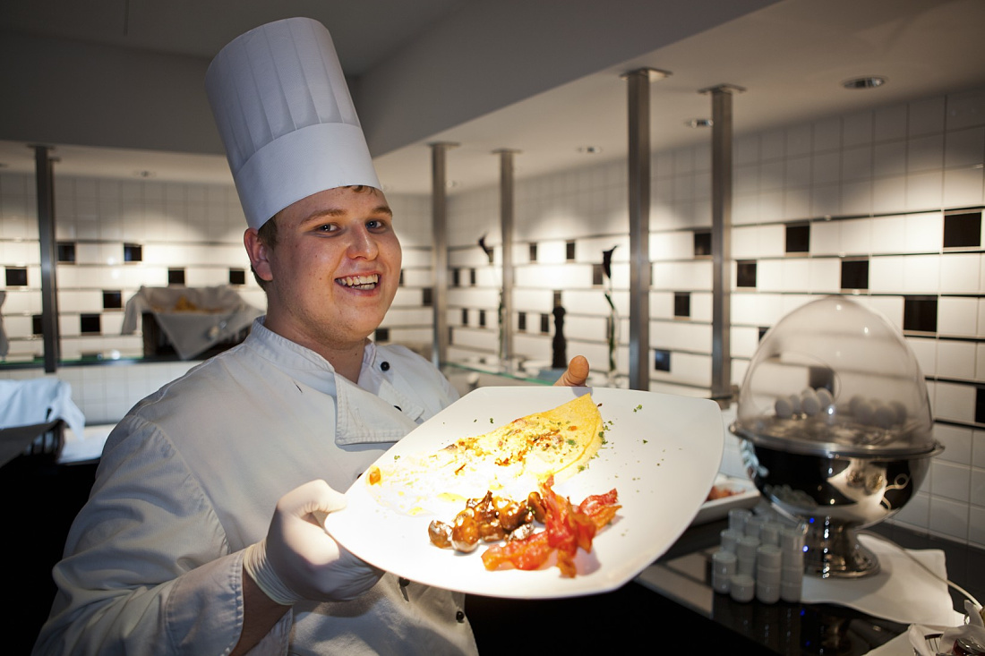 Chef presenting an omelet at Steigenberger Grandhotel Handelshof, Leipzig. ERCO lighting design for hospitality.