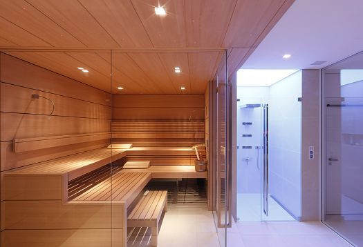 Sauna interior featuring wooden benches and glass walls, illuminated with ERCO LED lighting.