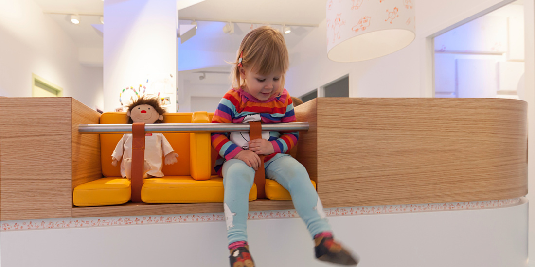 Child in the friendly waiting area of Uhlig Paediatric Practice, illuminated by ERCO LED lighting.