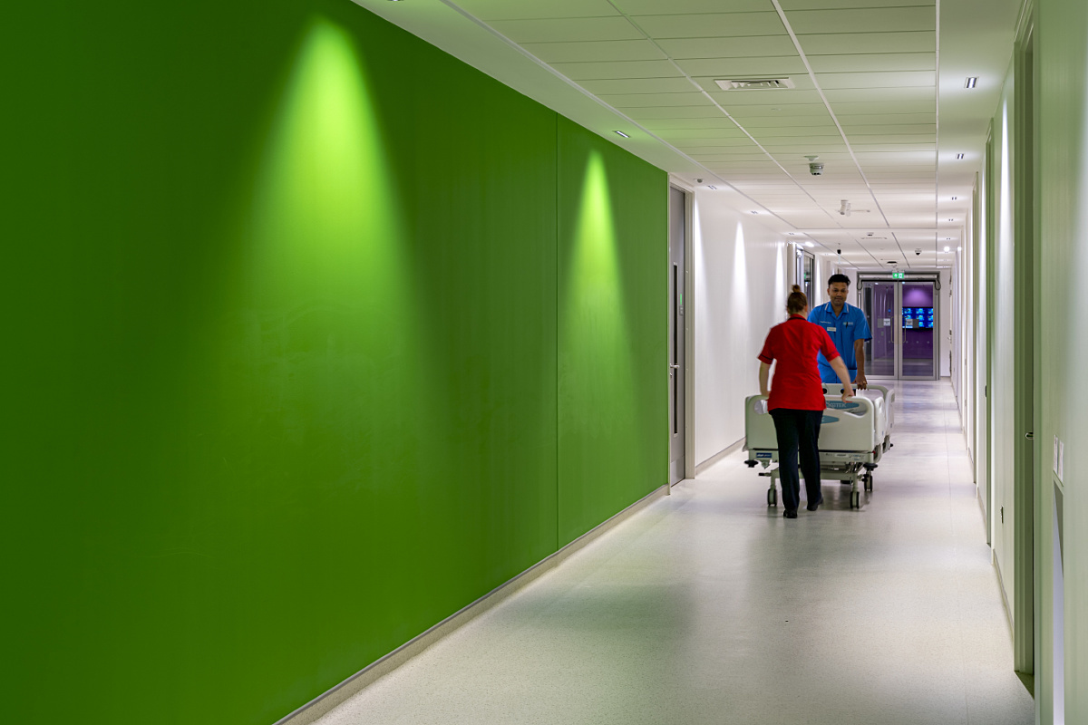 Ulster Hospital corridor with ERCO Compar lighting and staff moving a patient bed.