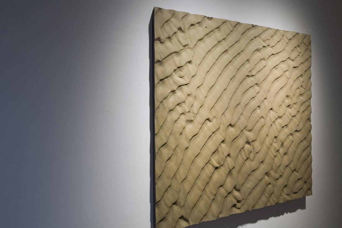 Sand-patterned artwork illuminated by LED spotlights at Vigo Gallery, London.