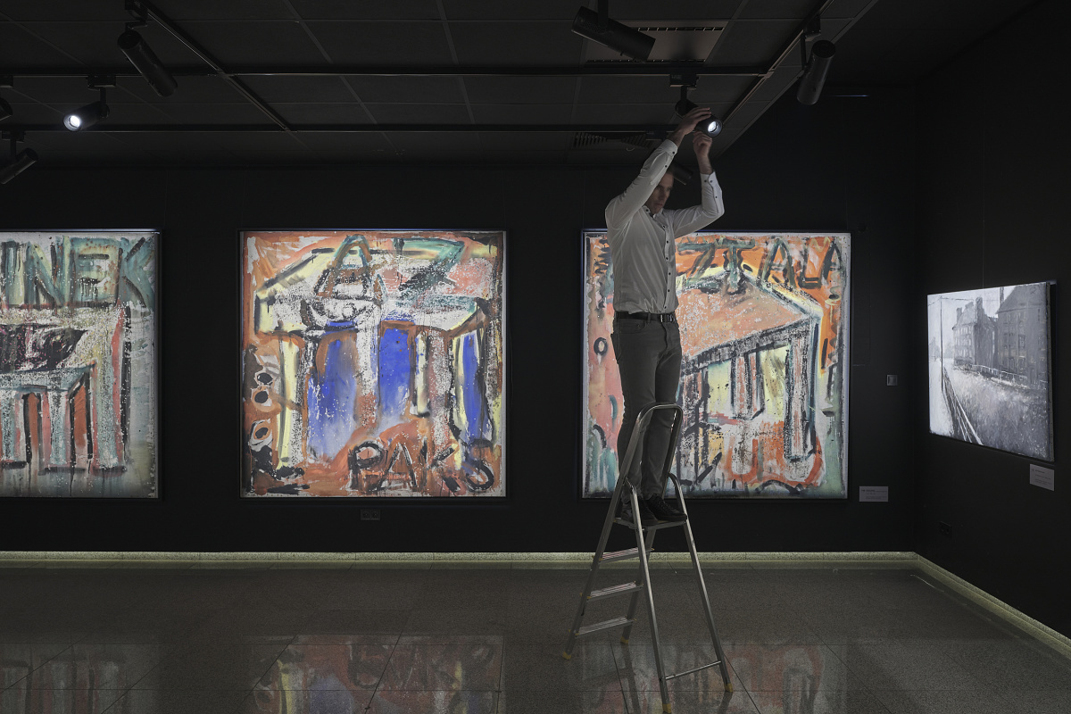 A man adjusts ERCO Eclipse spotlights in the Virág Judit Gallery, accentuating art for sale.