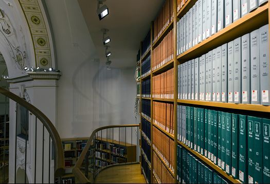 Vorarlberg State Library illuminated with ERCO LEDs, featuring bookshelves and a spiral staircase.