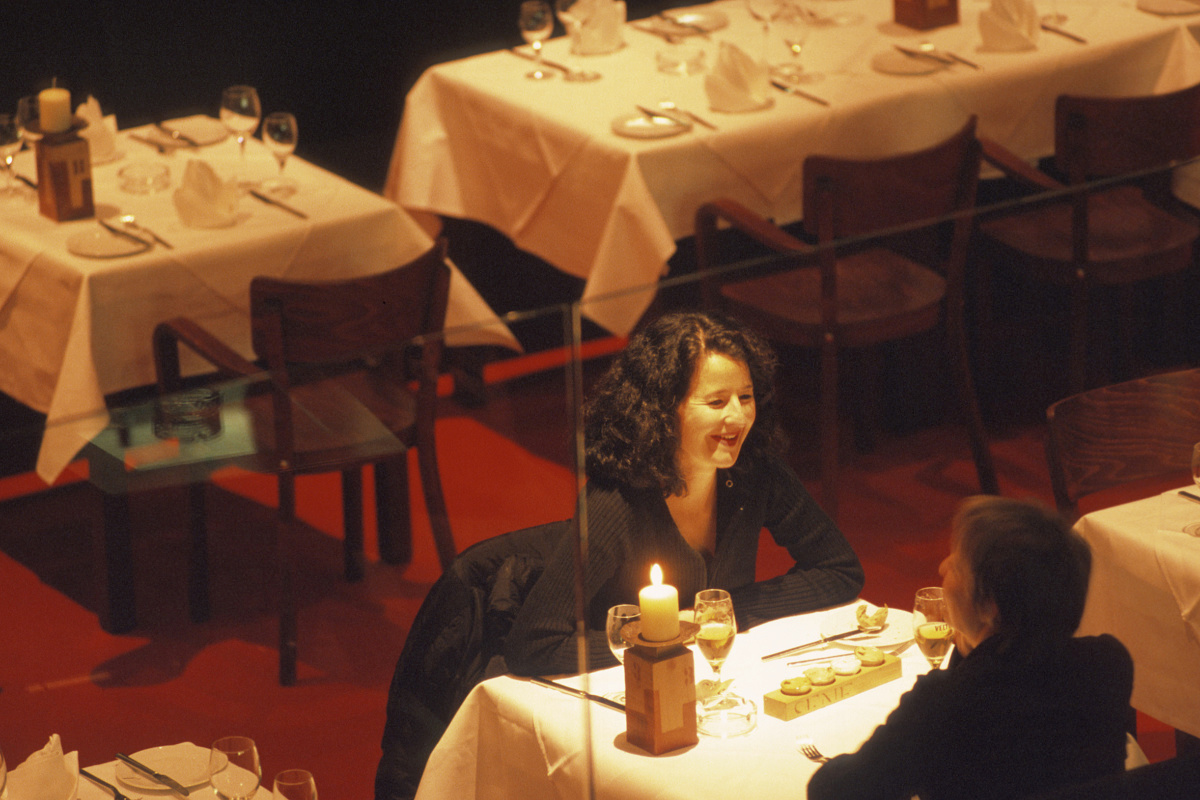 Woman enjoying the ambiance in a restaurant, enhanced by ERCO lighting.