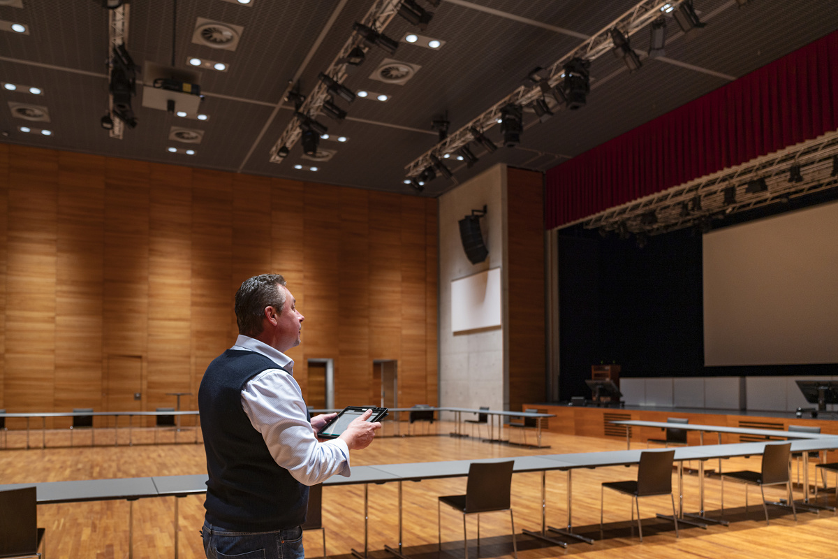 Mann steuert ERCO Casambi Leuchten mit Bluetooth in einem Konferenzraum.