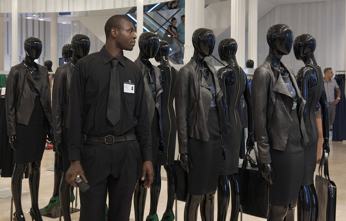 Zara store security guard with Optec spotlight-illuminated mannequins displaying fashion.
